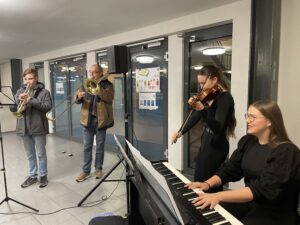 Schüler und Lehrer spielen auf Keyboard, Violine und Blechblasinstrumente ein Lied