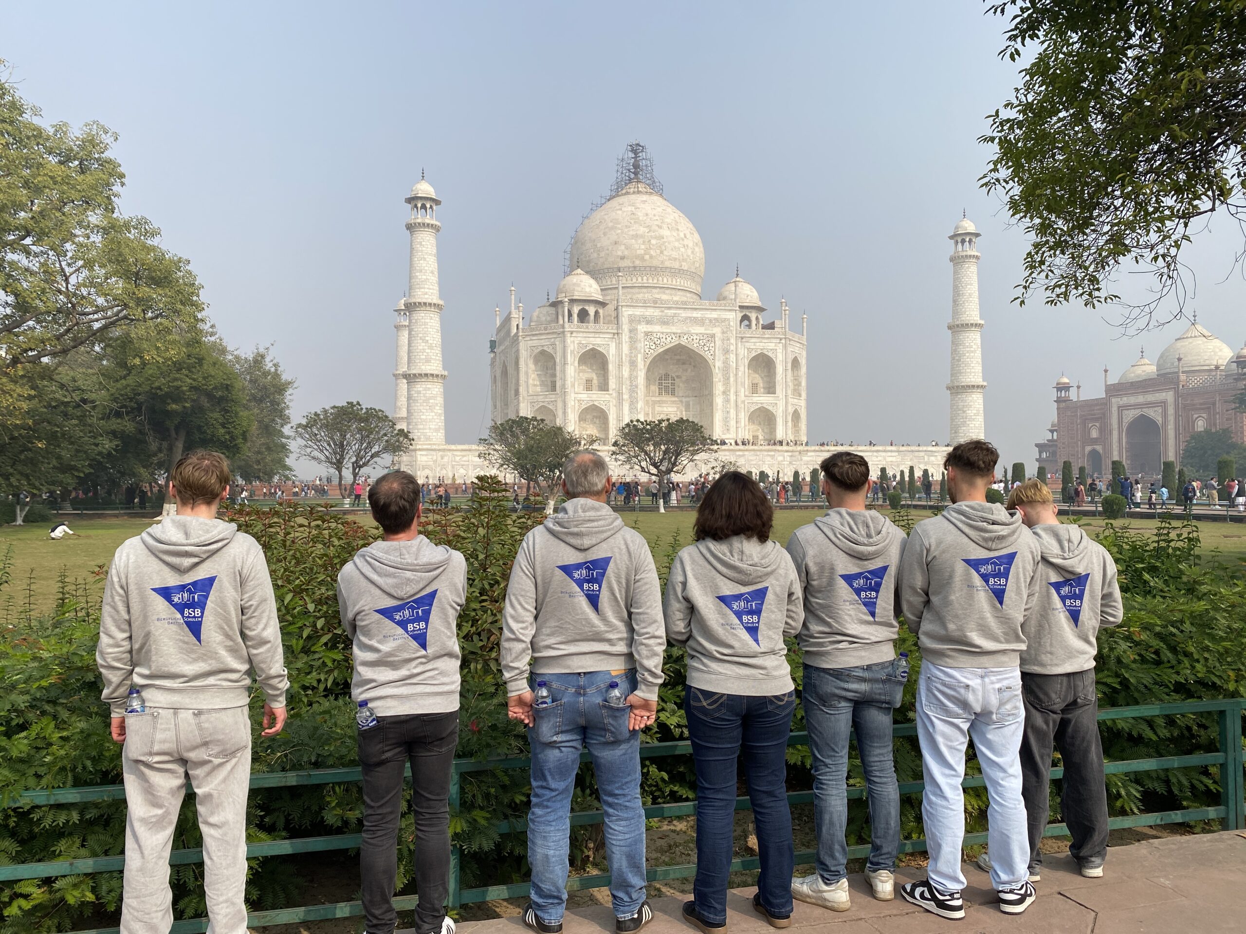 Gruppenfoto vor dem Taj Mahal mit dem Rücken zur Kamera um die neuen BSB Pullover mit dem Logo auf dem Rücken zu präsentieren